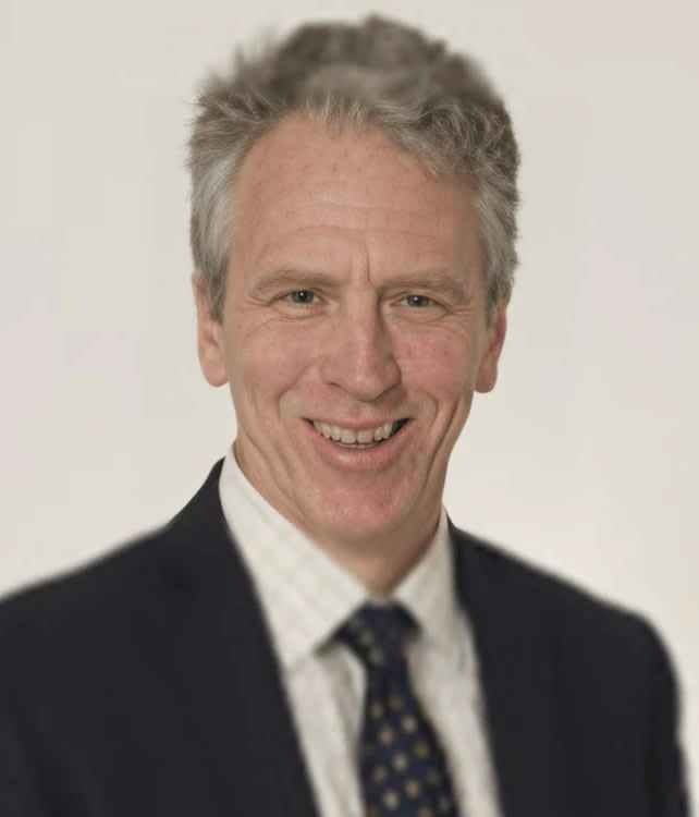 A man in a suit and tie is smiling for the camera