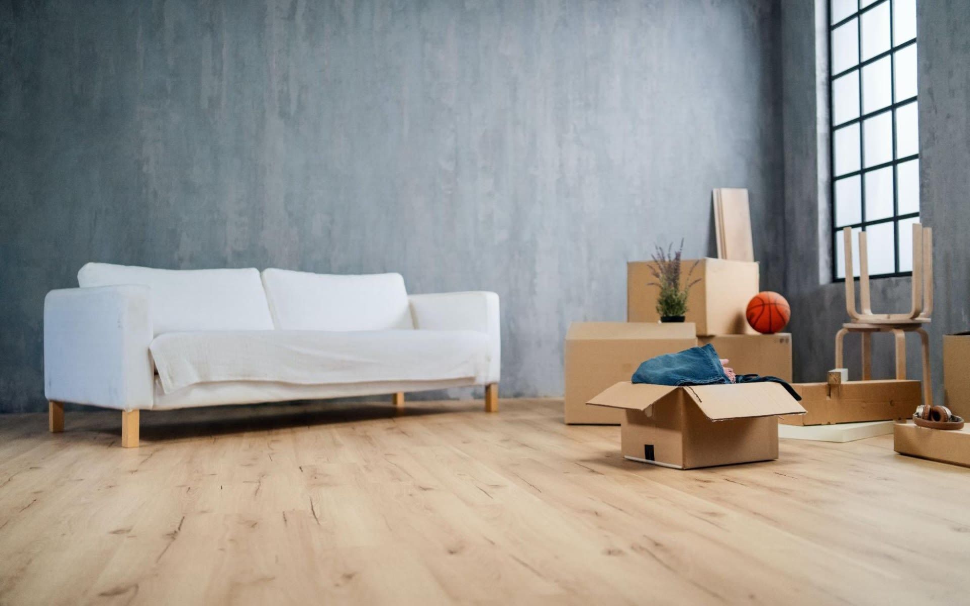 A living room filled with cardboard boxes and a white couch.