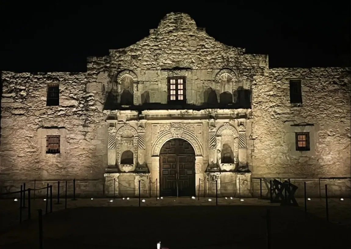 A large stone building is lit up at night.