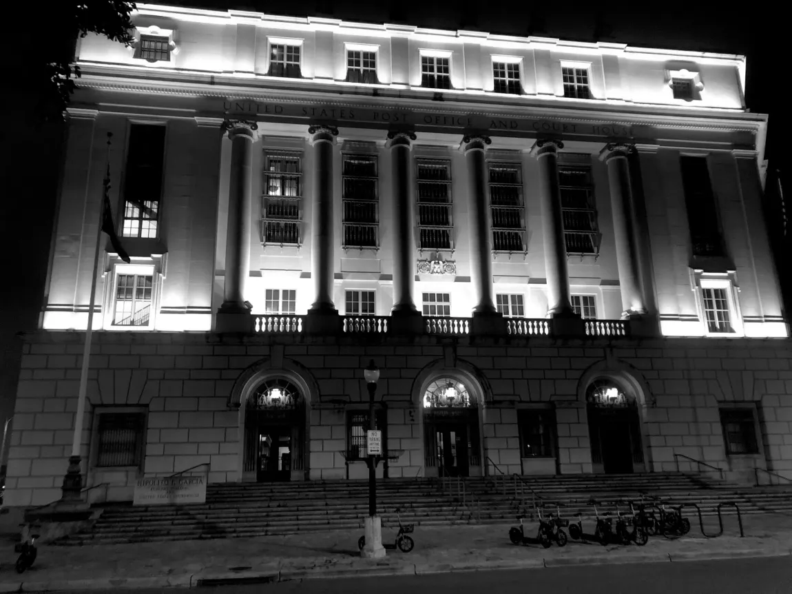 A black and white photo of a large building lit up at night