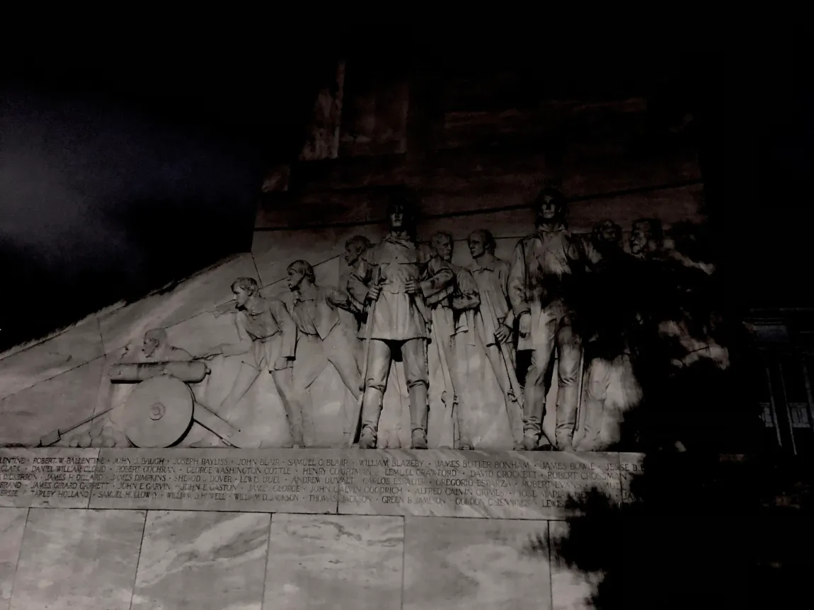 A statue of a group of people standing next to each other in the dark.