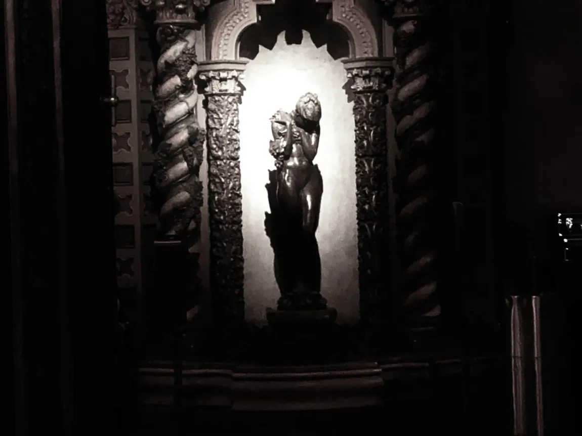 A black and white photo of a statue in a dark room