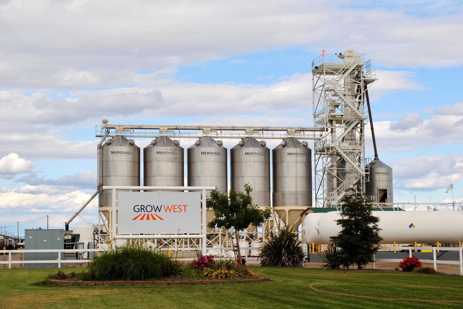 Grain silos and processing facility under a cloudy sky. 