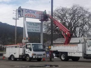 Two workers on lifts installing a sign for 