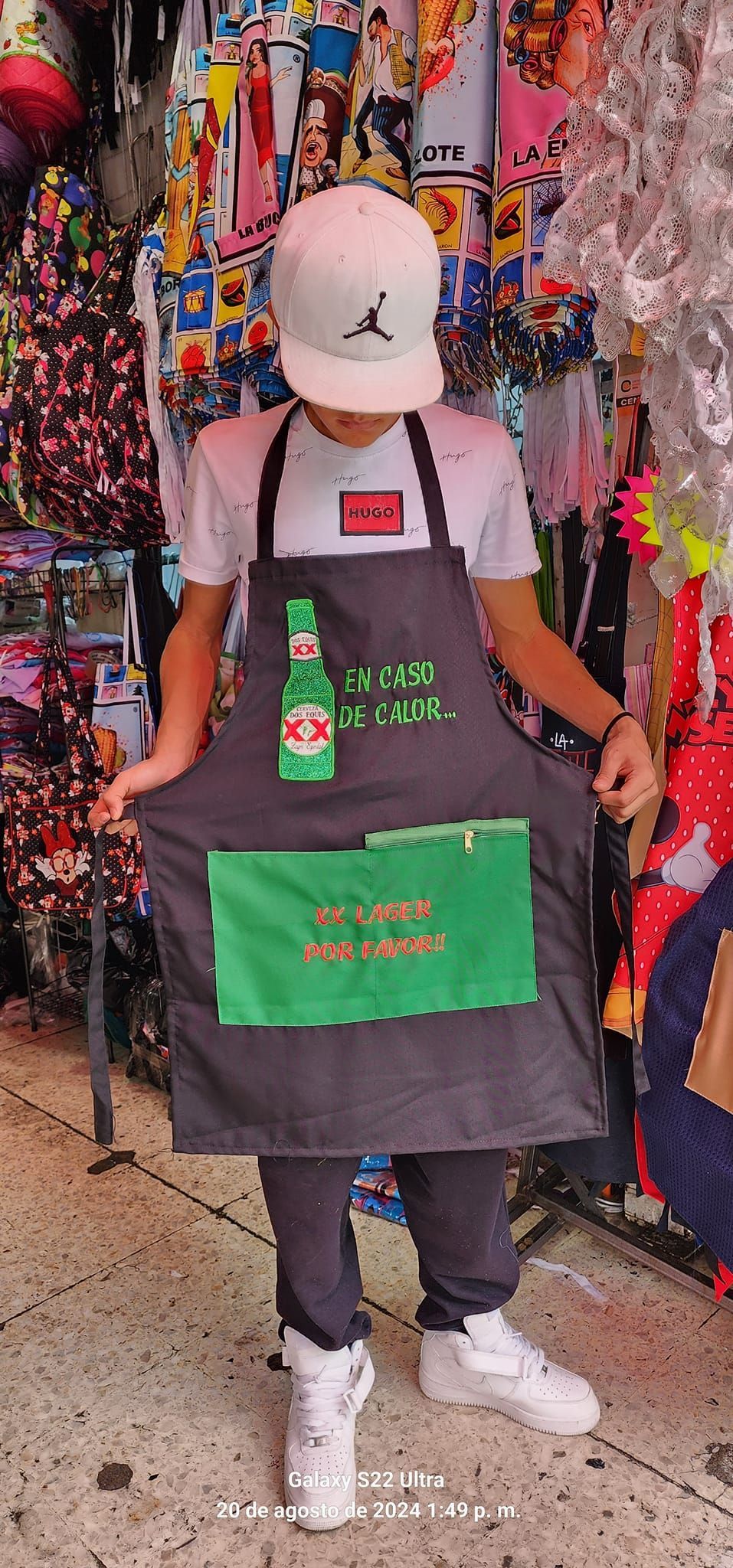 Un hombre que lleva un delantal con una botella de cerveza encima está parado en una tienda.