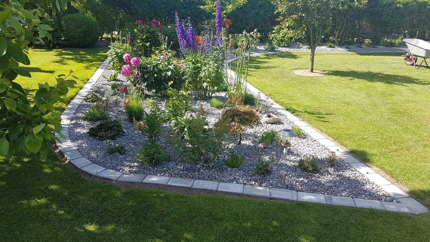 En have fyldt med blomster og sten i form af en trekant.