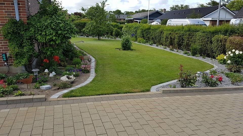 En muret indkørsel fører til en frodig grøn have