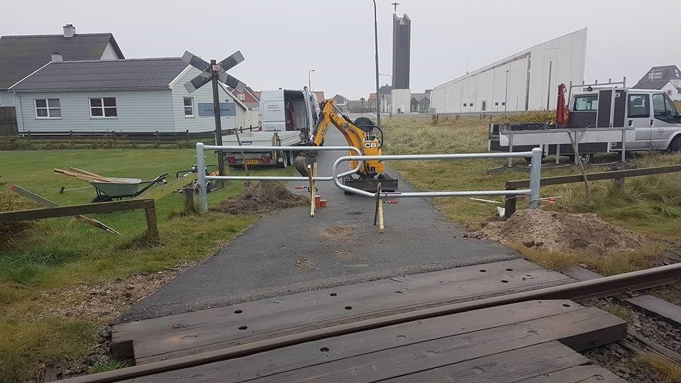 En togbane med et hegn og et hus i baggrunden.