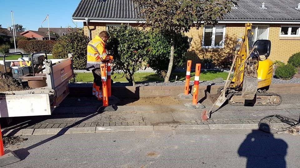 En bygningsarbejder arbejder på et fortov foran et hus