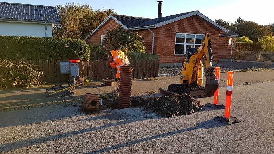 En mand er ved at grave et hul i jorden foran et hus