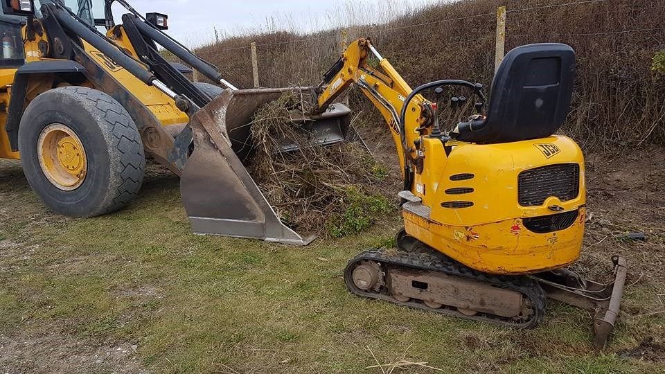 En lille gul gravemaskine bliver brugt til at grave et hul i jorden.