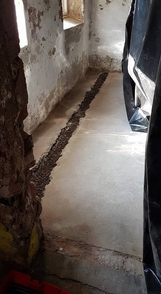 Et rum med betongulv og murstensvæg.