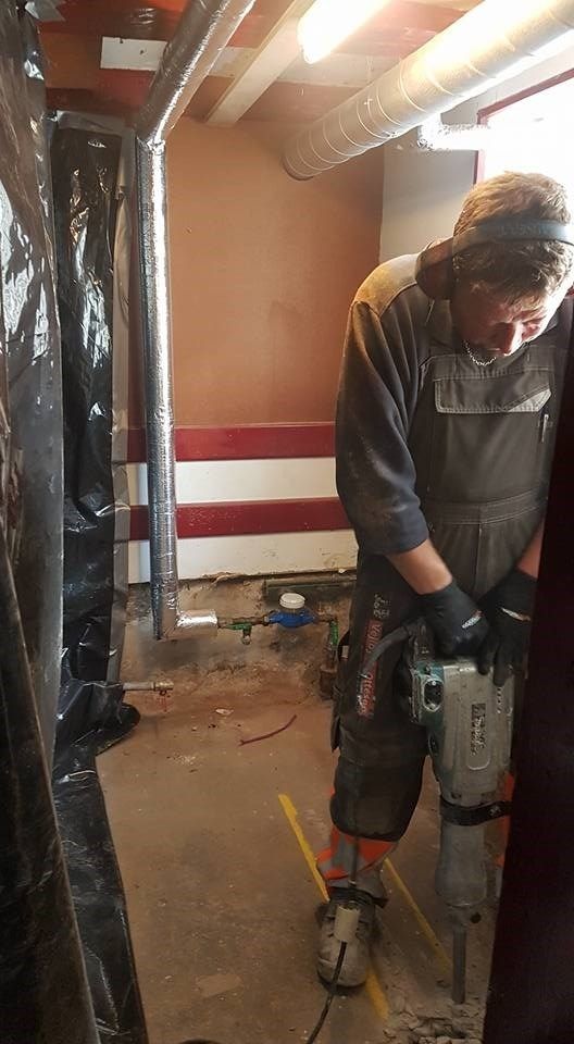 En mand bruger en hammer til at bore et hul i en væg.