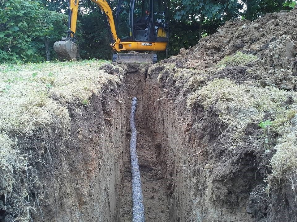 En gul gravemaskine er ved at grave et hul i jorden.