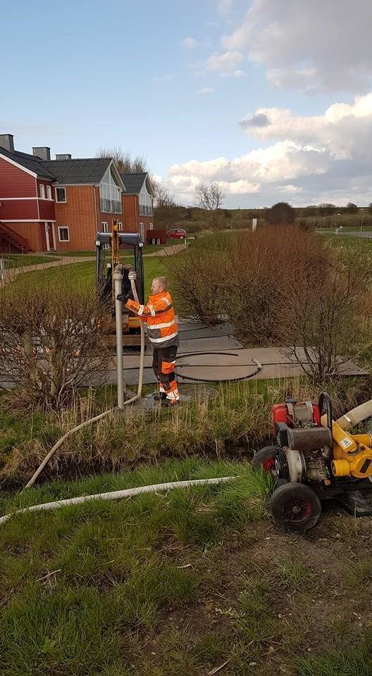 En mand står ved siden af ​​en gul traktor på en mark.