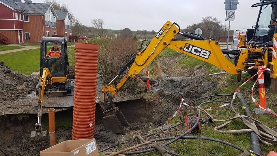 En gul jcb gravemaskine er ved at grave et hul i jorden