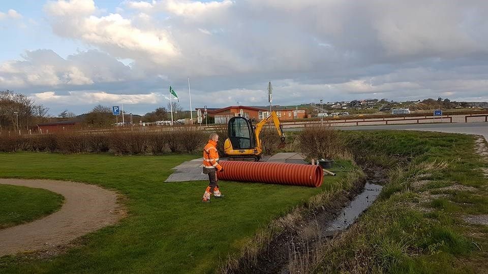 En mand står ved siden af ​​et stort rør i en park.
