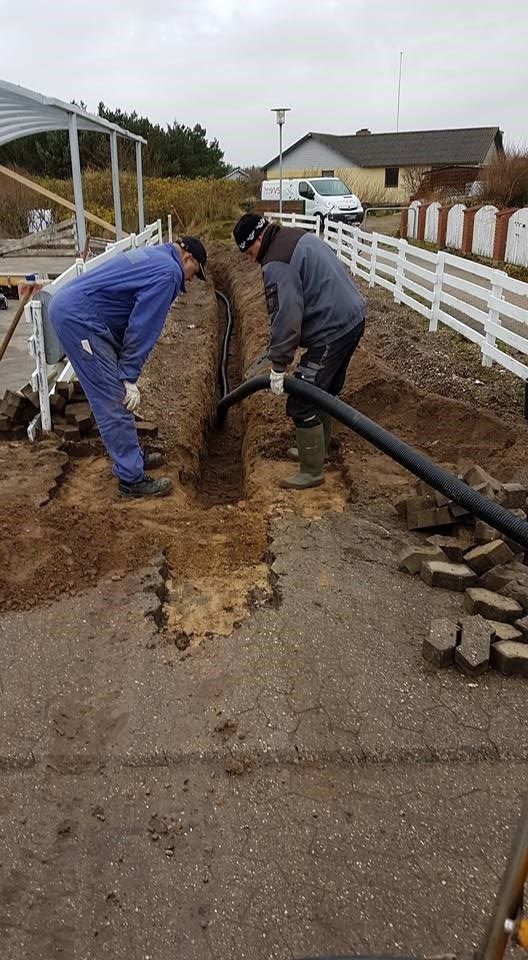 To mænd arbejder på et rør i jorden.