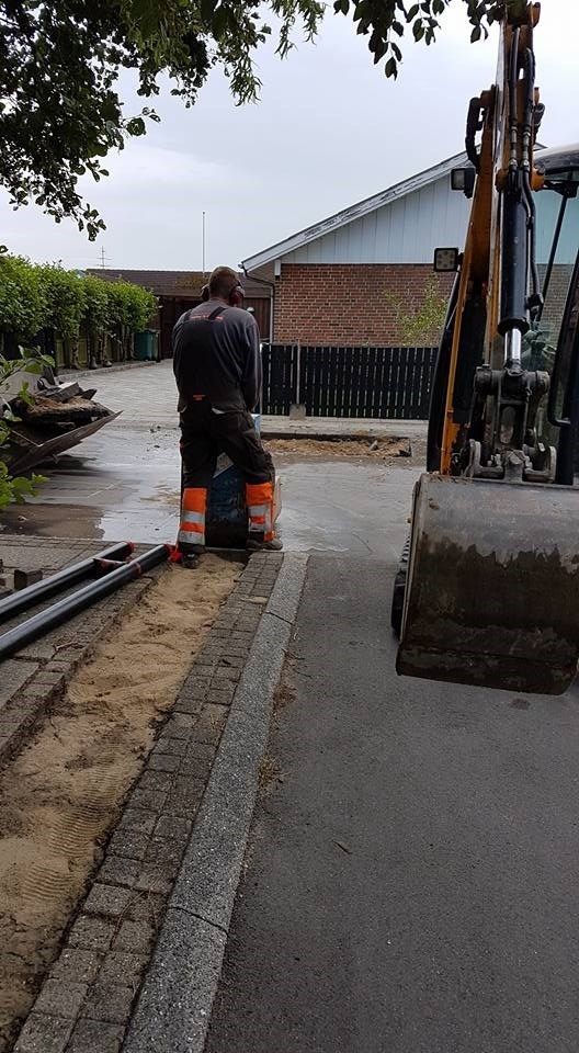 En mand står ved siden af ​​en bulldozer i siden af ​​vejen.
