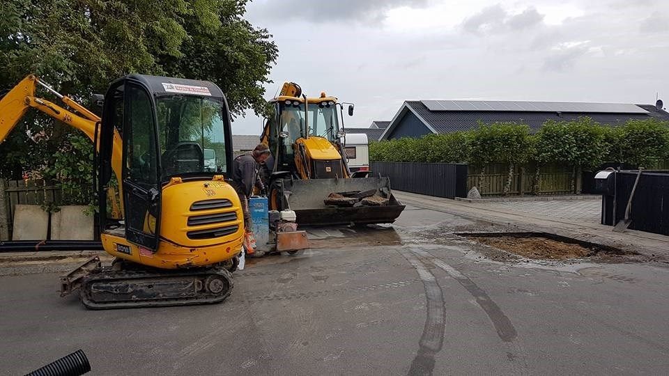 Et par entreprenørkøretøjer holder parkeret i siden af vejen.