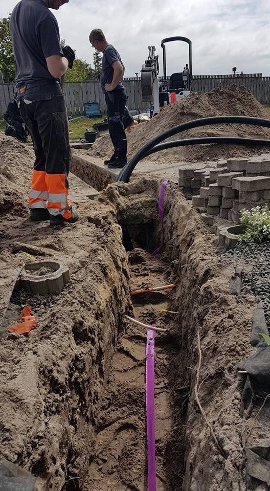 Et par mænd står i en rende i jorden.