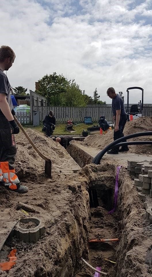 En gruppe mænd graver en rende i jorden.