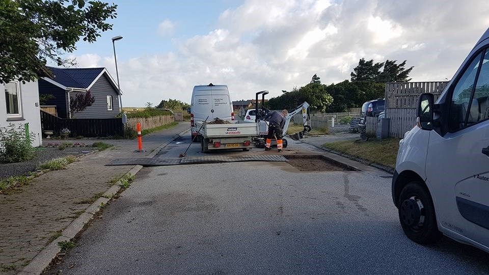 En hvid varevogn holder parkeret i siden af ​​vejen ved siden af ​​en lastbil.