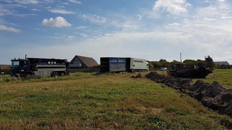 En dumper og en trailer er parkeret på en græsmark.