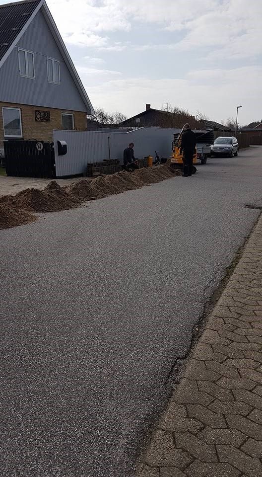 En mand står ved siden af ​​en bunke jord i siden af ​​en vej.