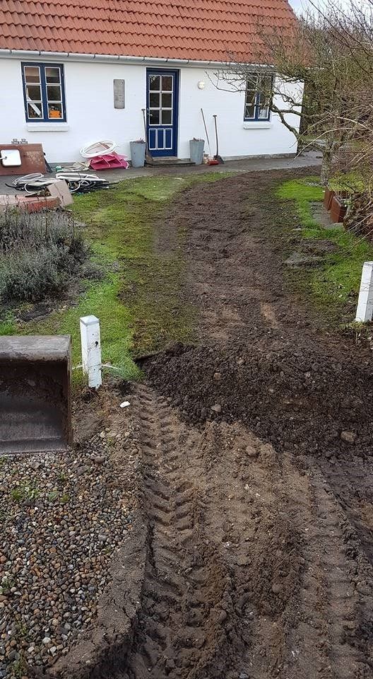 Et hvidt hus med en blå dør er omgivet af snavs og græs.