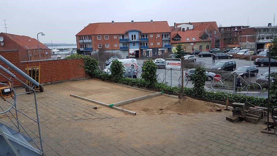 En parkeringsplads med mange biler parkeret foran en bygning.