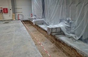 Et rum med et betongulv og en betonvæg beklædt med plastik.