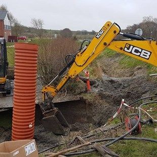 En gul jcb gravemaskine er ved at grave et hul i jorden.