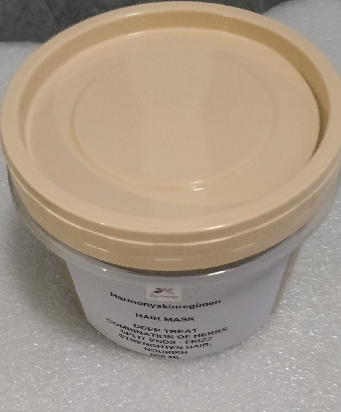 A container of hair mask with a tan lid