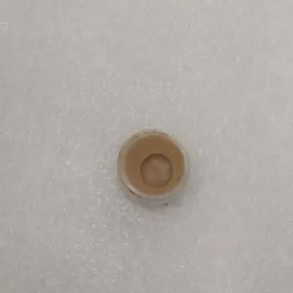 A small round object is sitting on a white surface.