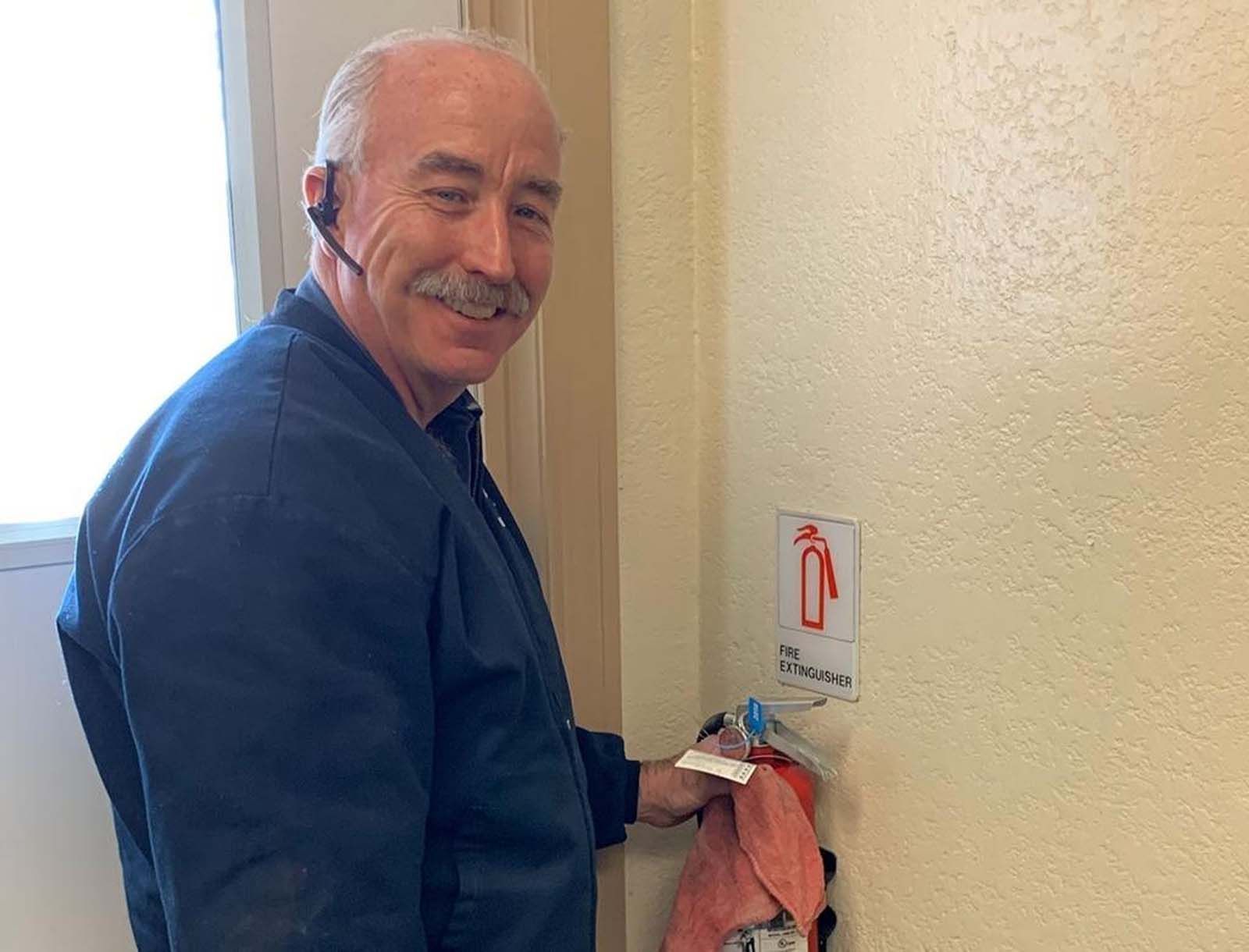 A man wearing a headset is standing next to a fire extinguisher.