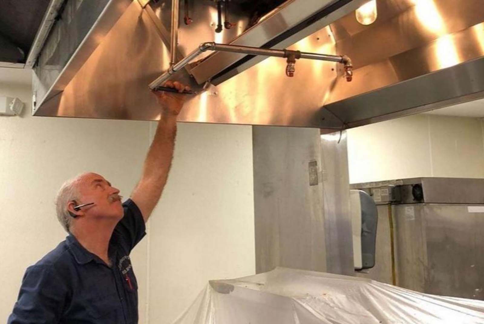 A man is looking up at the ceiling of a kitchen.