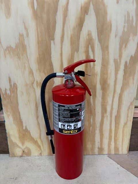 A red fire extinguisher is sitting on a wooden surface