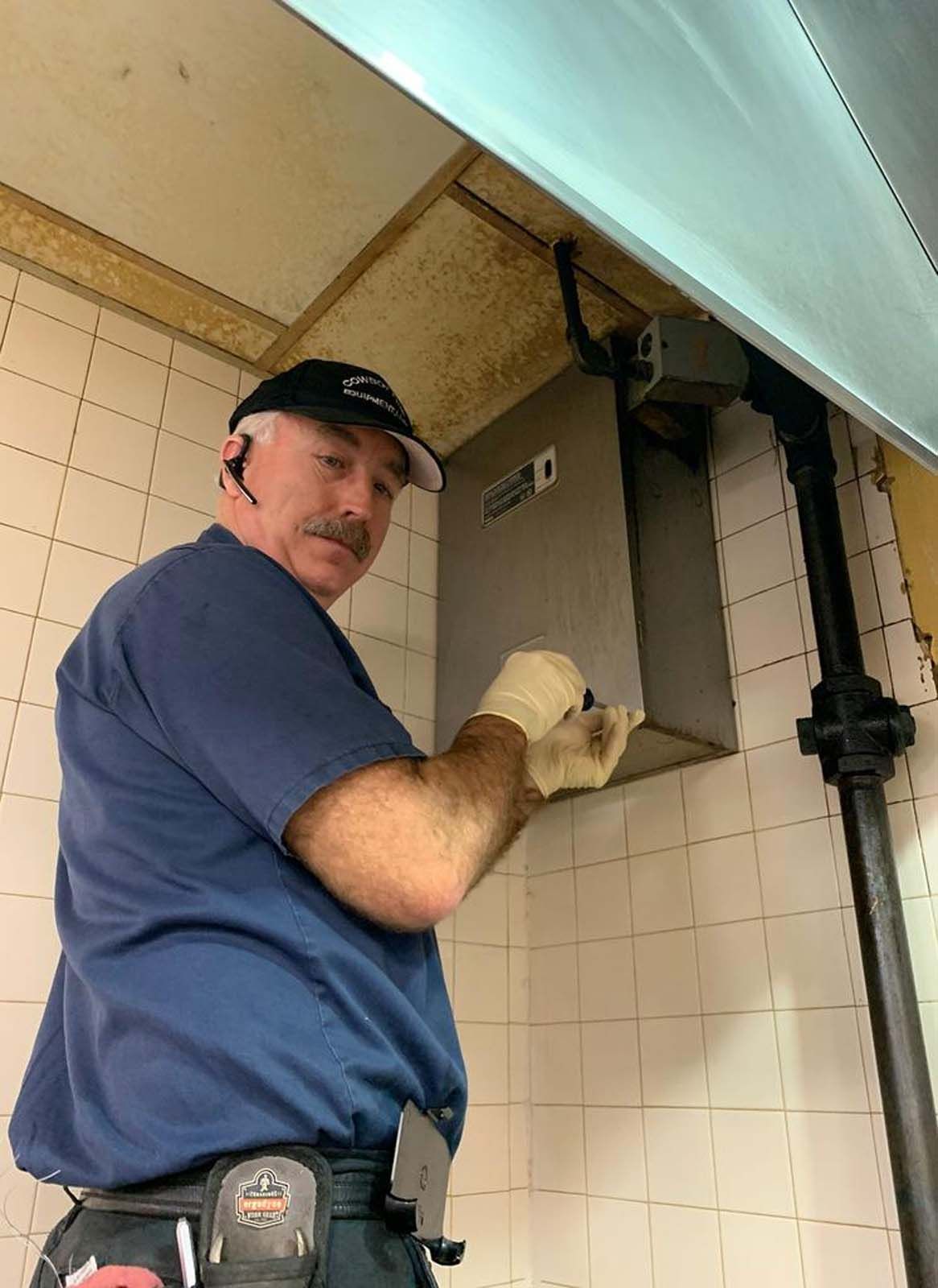 A man in a blue shirt is working on a wall.
