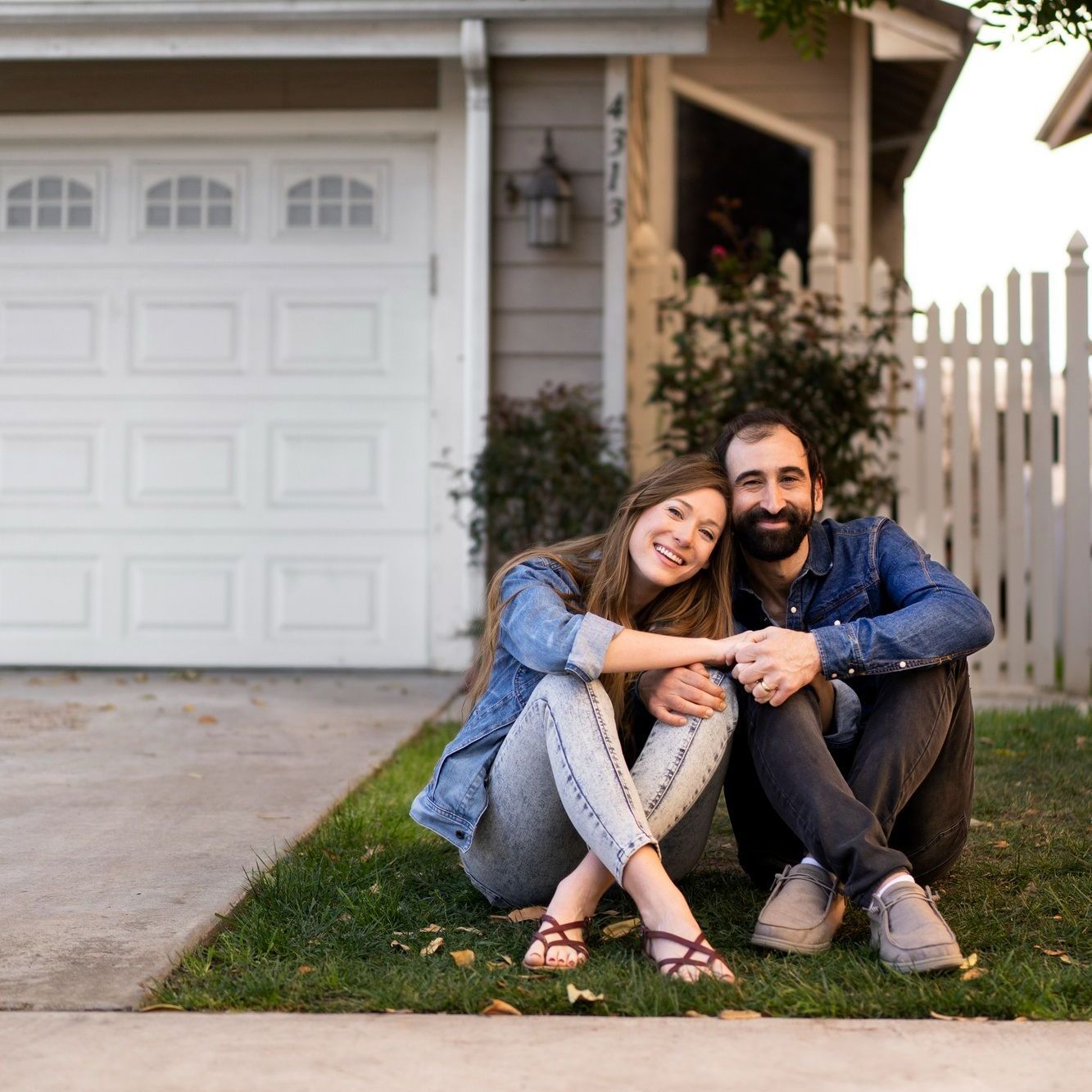 A man and a woman are sitting on the grass in front of a garage door