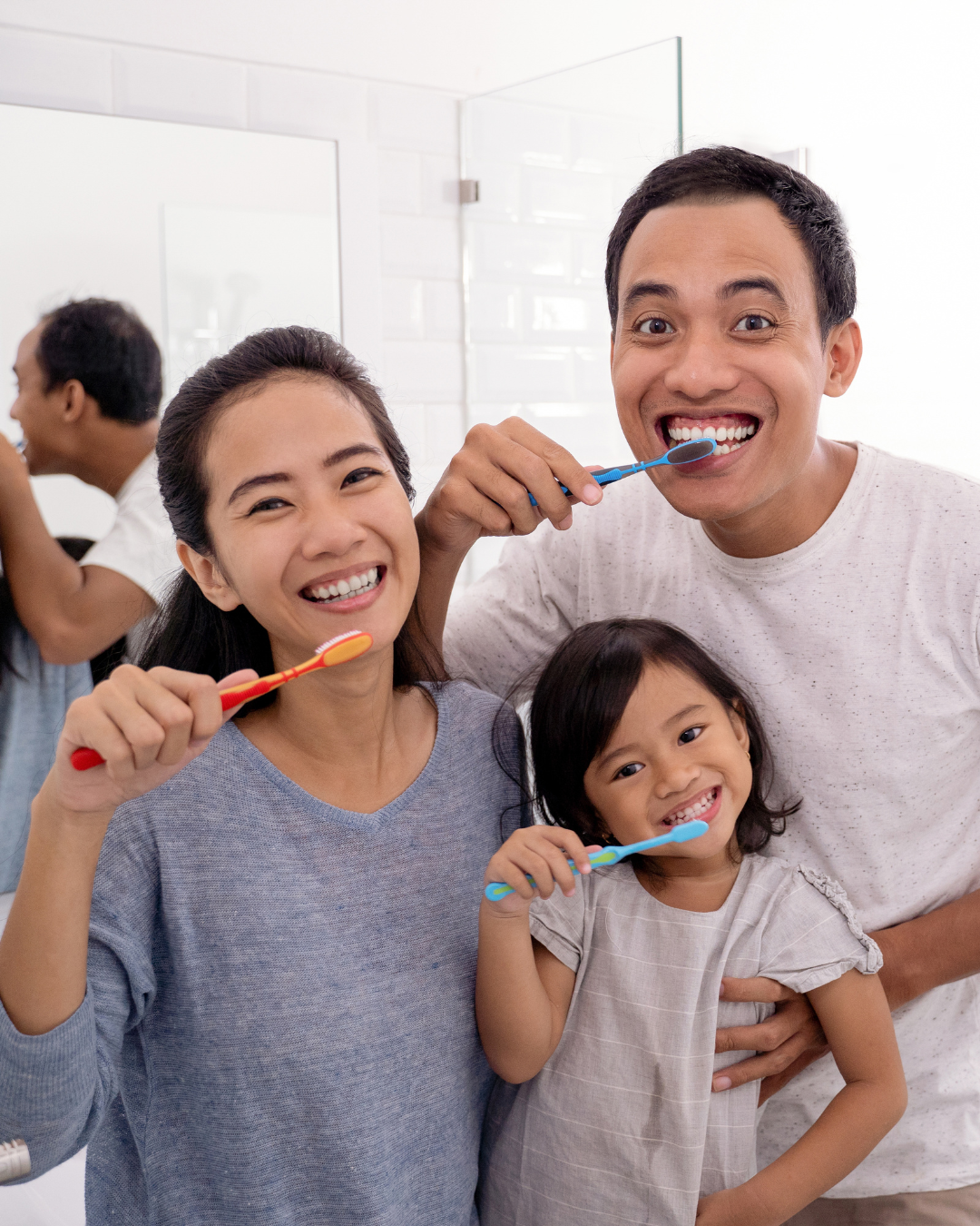 Trois personnes se brossent les dents ensemble dans une salle de bains, souriant à l'objectif.