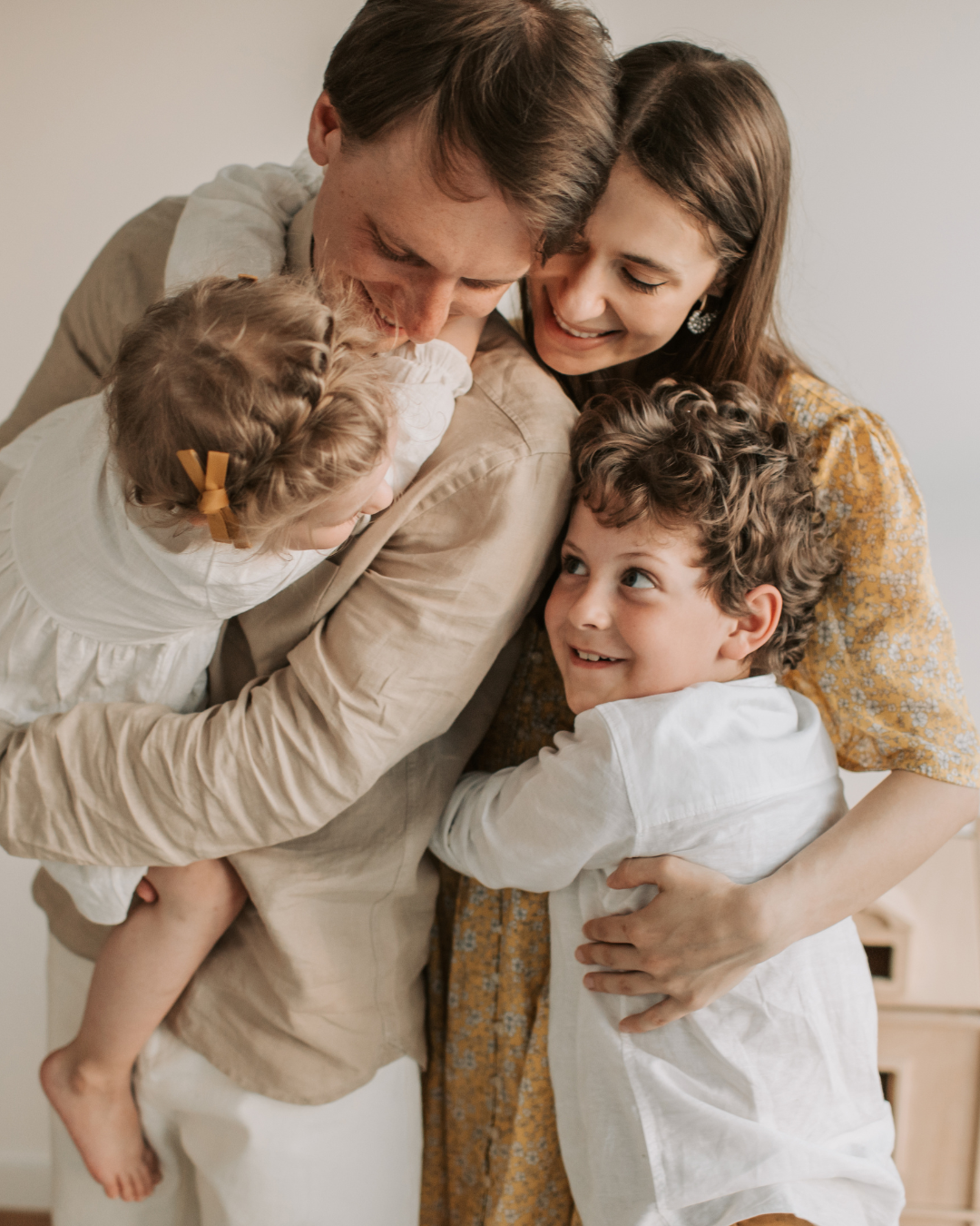 Une famille de quatre personnes s'enlace chaleureusement, les parents tenant leur jeune enfant