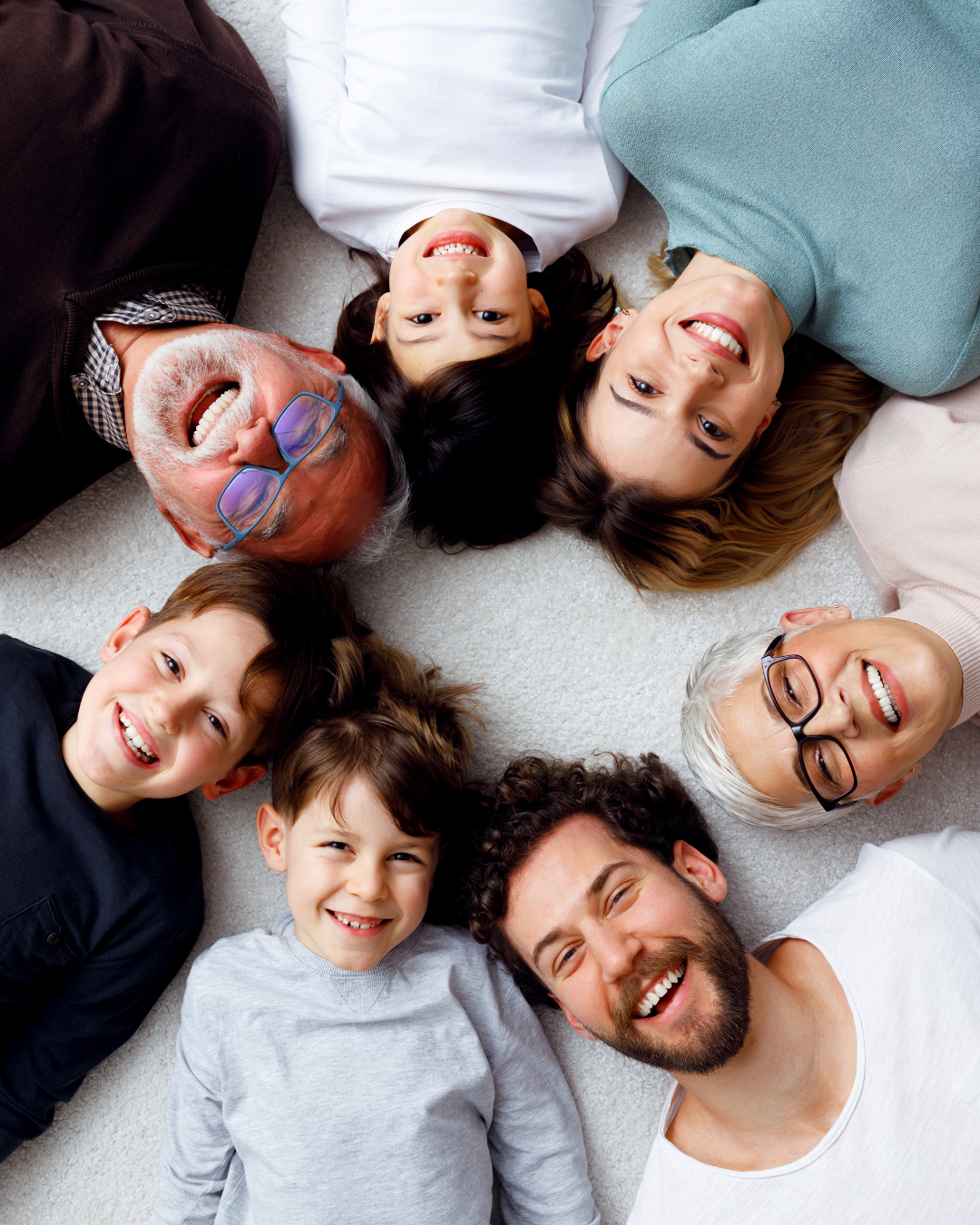 Un groupe de personnes d'horizons divers, allongées en cercle sur un fond blanc, souriant toutes vers la caméra.