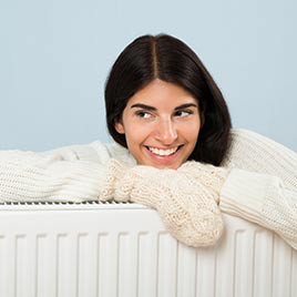 Woman In Sweater Leaning On Radiator — HVAC Hampton in Yorktown, VA