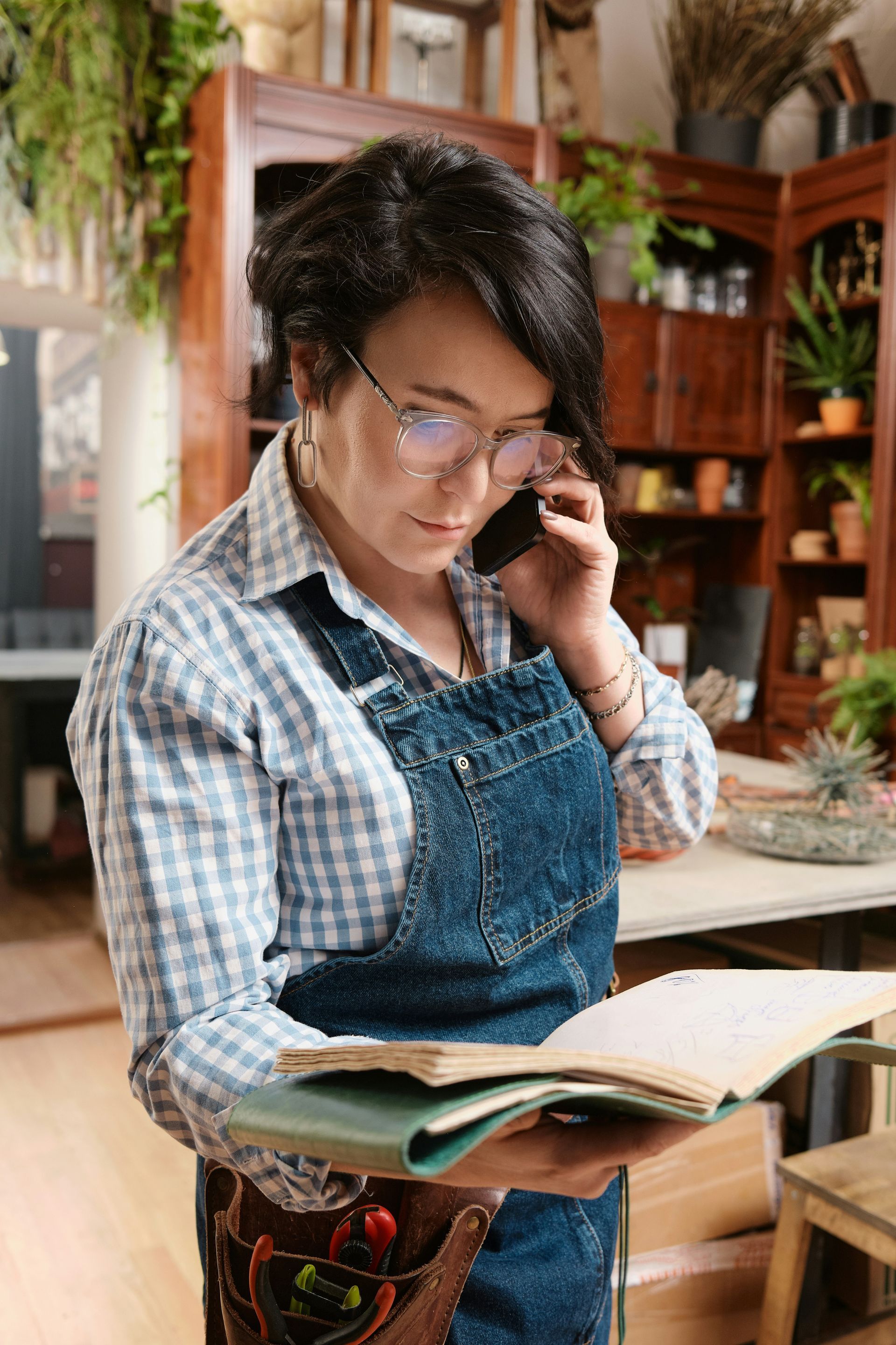 Man in apron reading a note while on a phone outside a gourmet shop