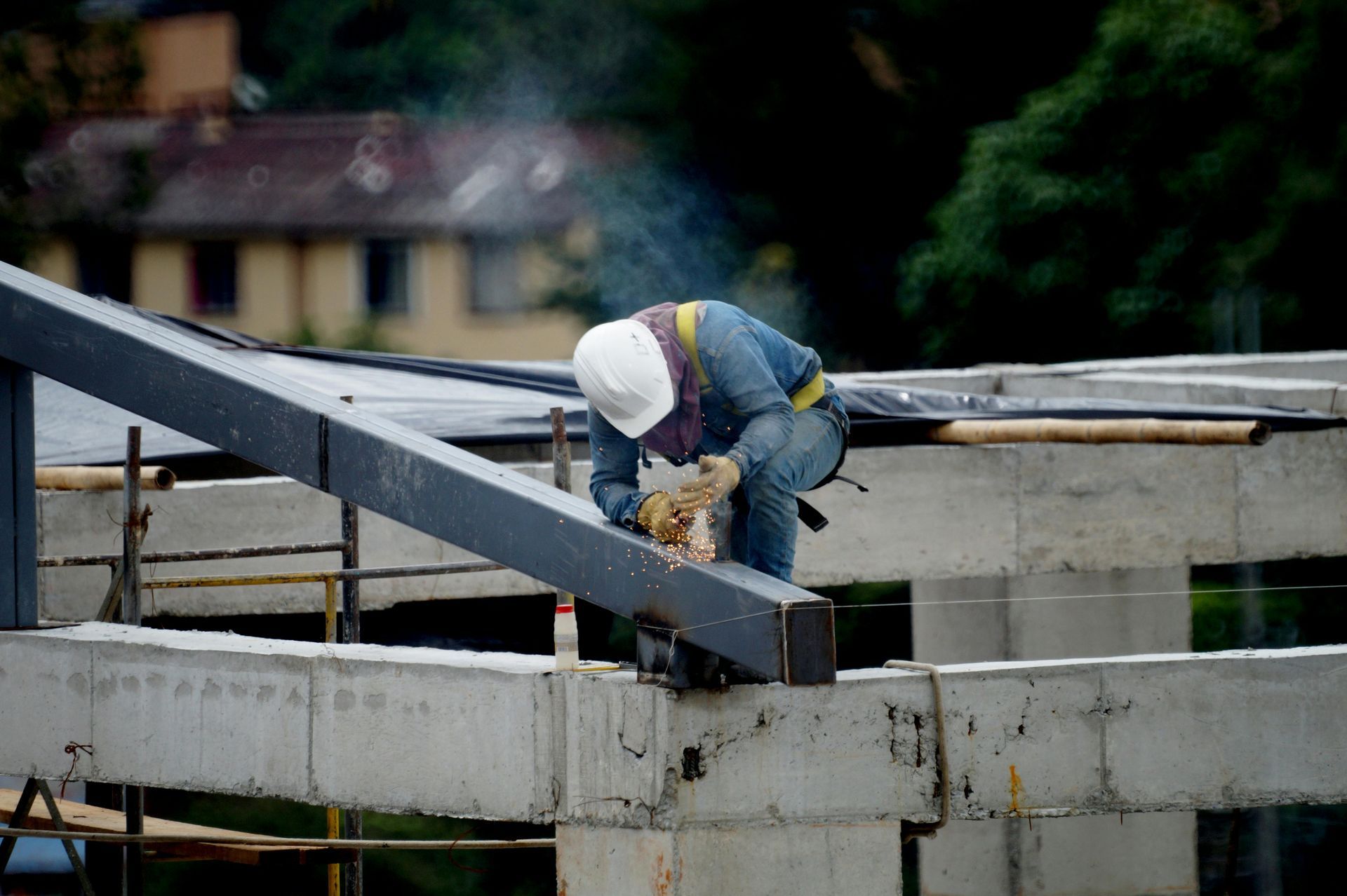 Construction worker in white hard hat working on a steel beam at a building site