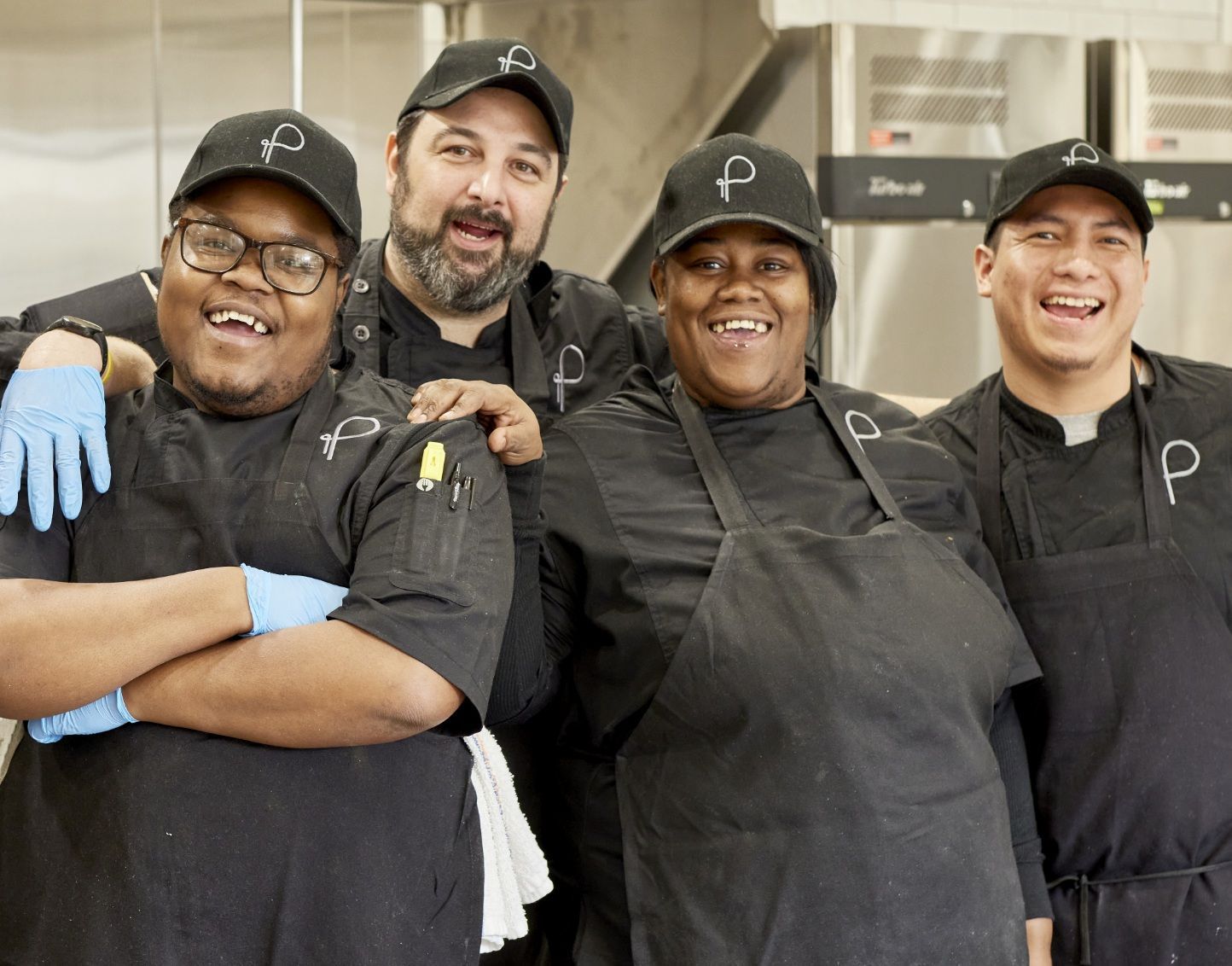 A group of chefs are posing for a picture in a kitchen.