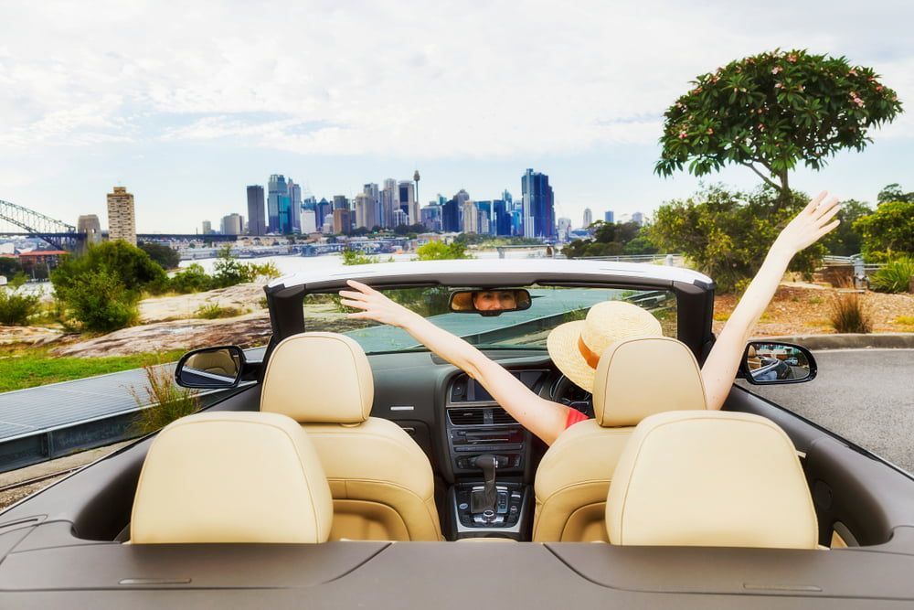 A Woman Is Sitting In A Convertible Car With Her Arms Outstretched — COOTA Automotive Services In Ballarat East, VIC