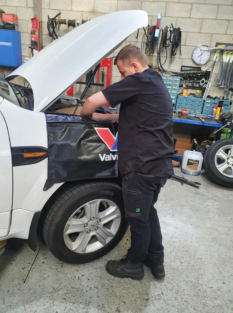 A Man Is Working On A White Truck With The Hood Up In A Garage — COOTA Automotive Services In Ballarat East, VIC