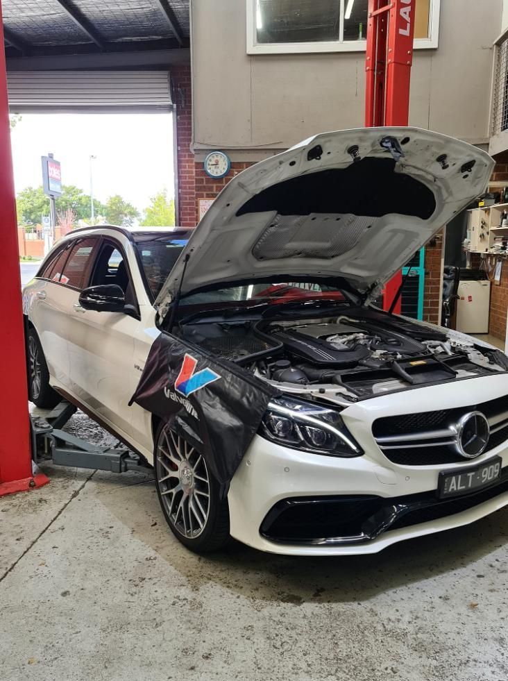 A White Mercedes Benz With The Hood Open Is Sitting On A Lift In A Garage — COOTA Automotive Services In Ballarat East, VIC
